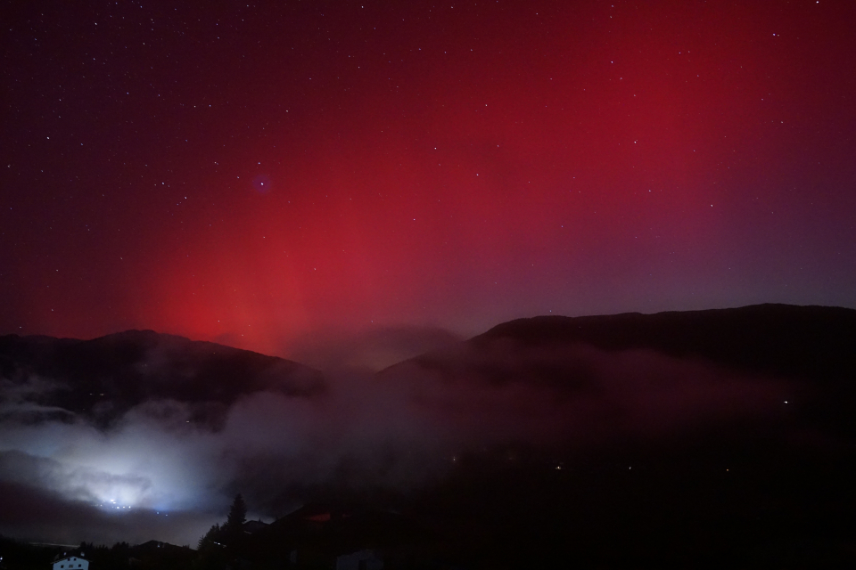 rötliche Polarlichter bei Sternenhimmel. Im Vordergrund der Ort Kartitisch (osttirol) bei Nacht.