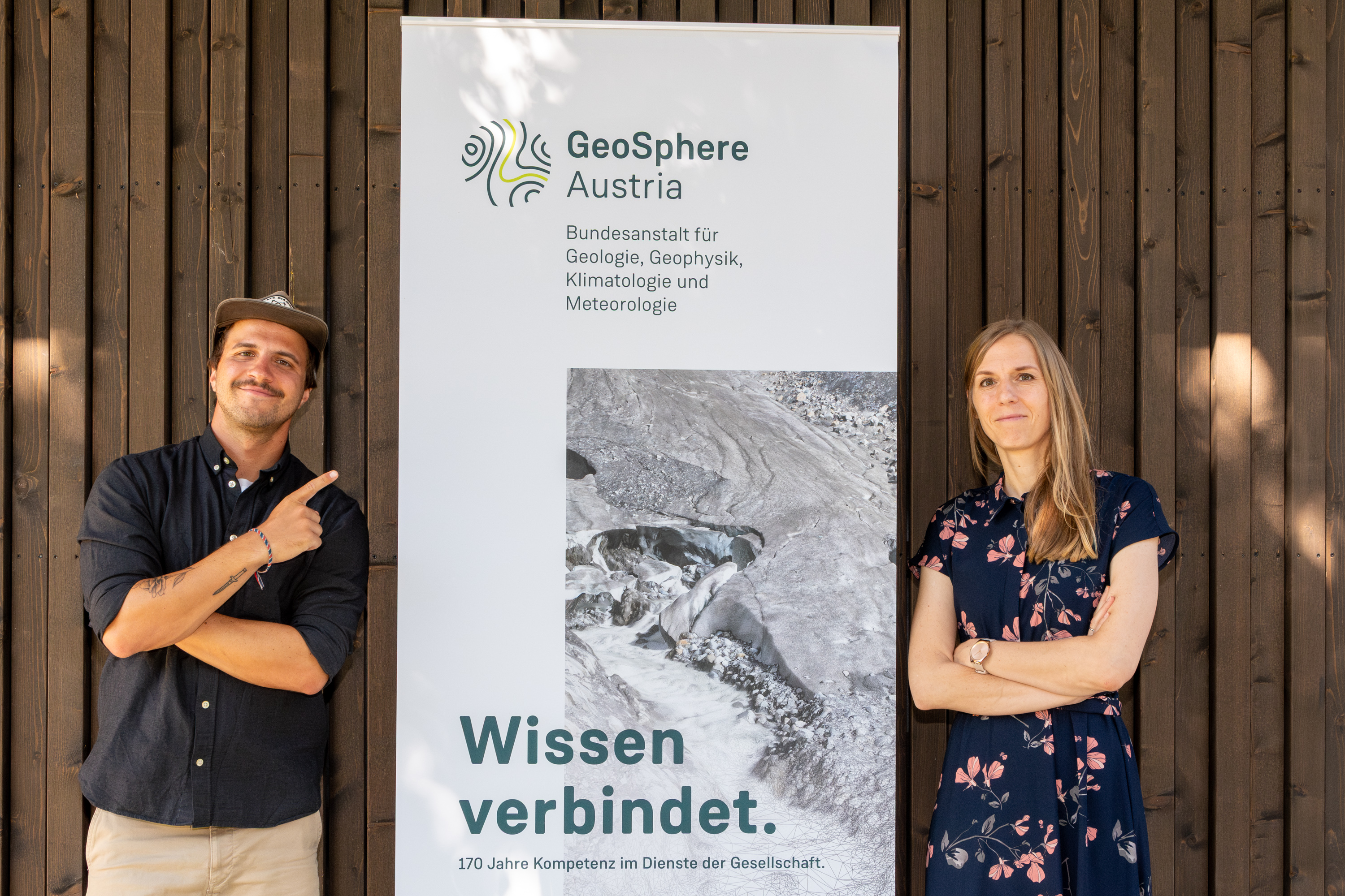 2 people in front of a wooden wall