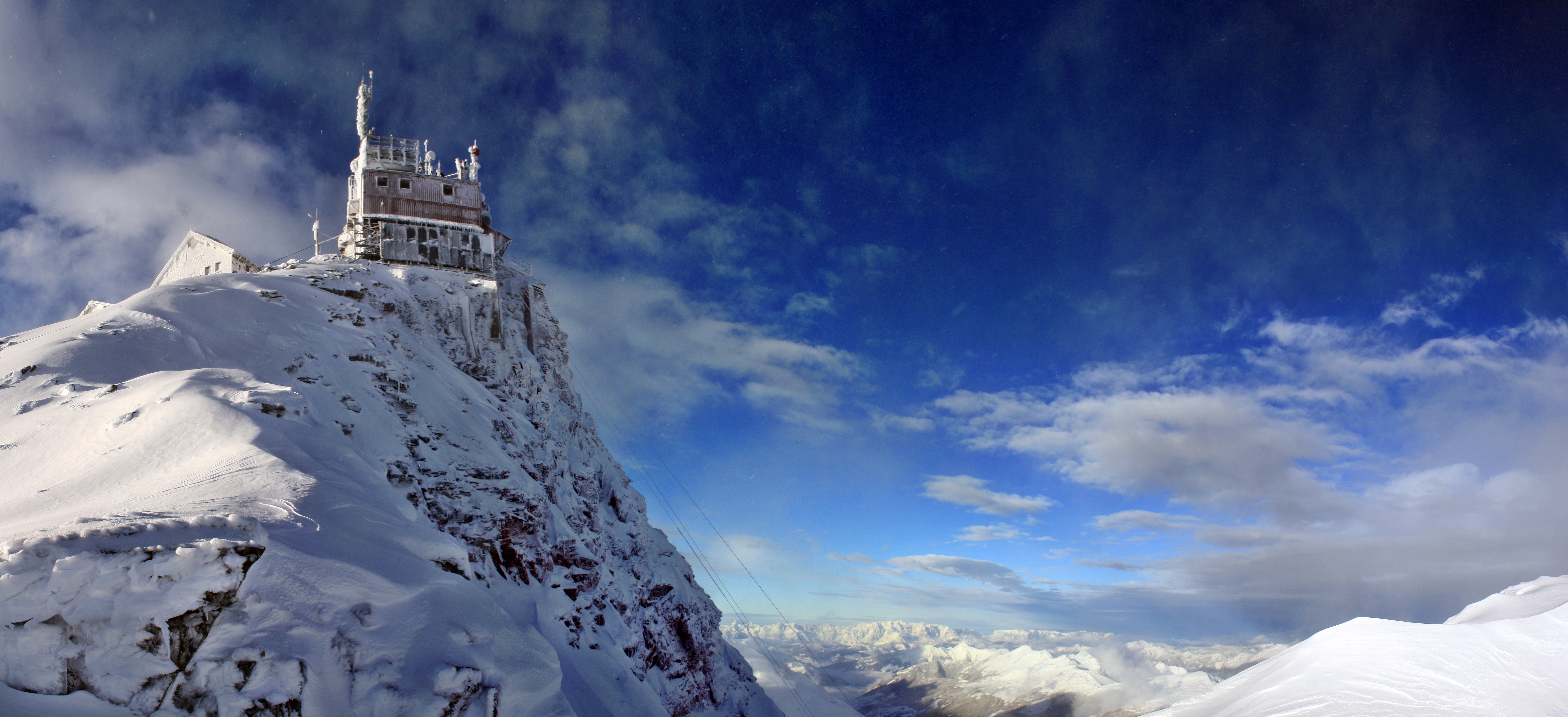 Das Gebäude des Sonnblick Observatoriums am Gipfel des Hohen Sonnblick (3.106 m Höhe). Im Hintergrund blauer Himmel mit Wolken.