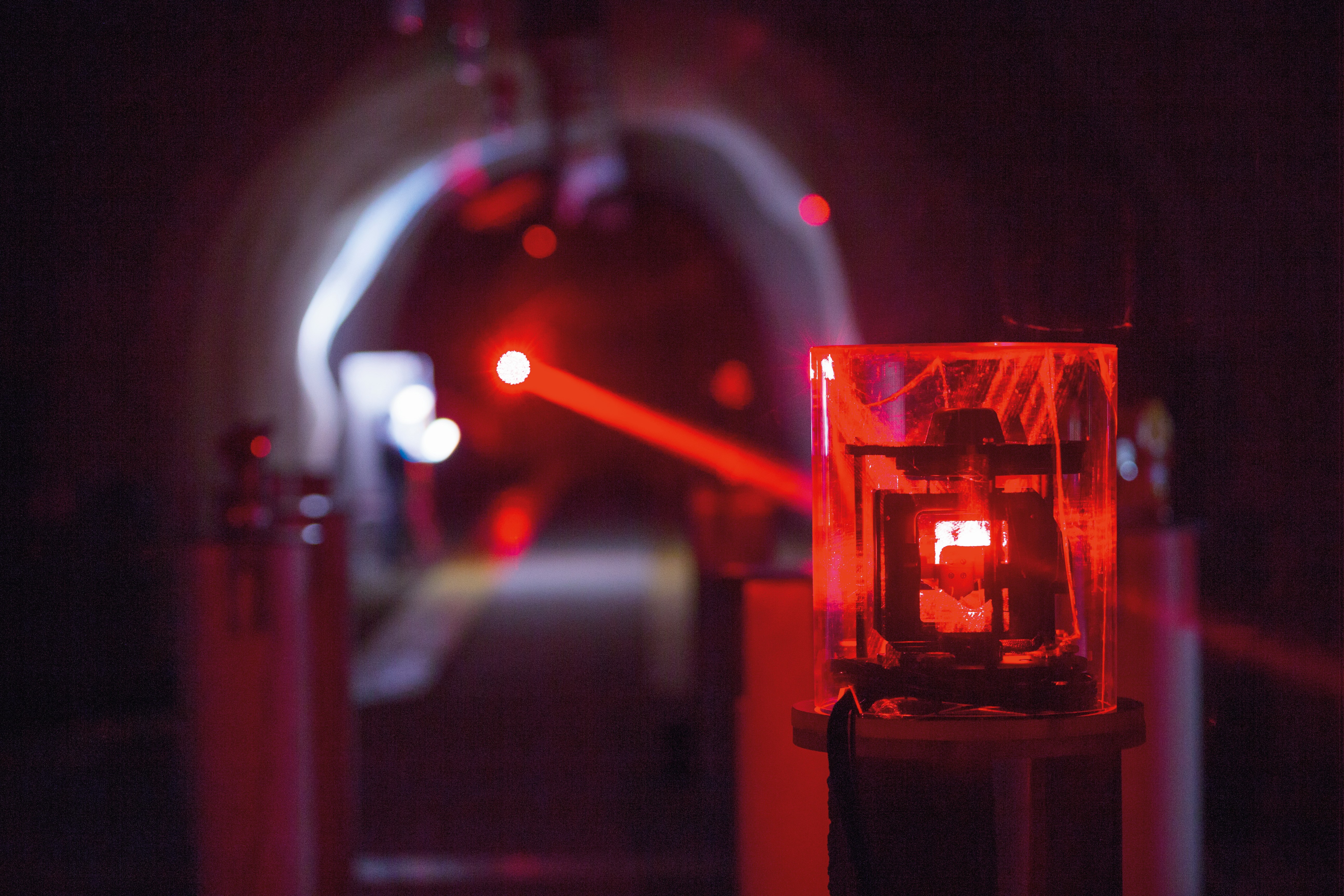 A red laser beam hits a target plate in an underground tunnel.