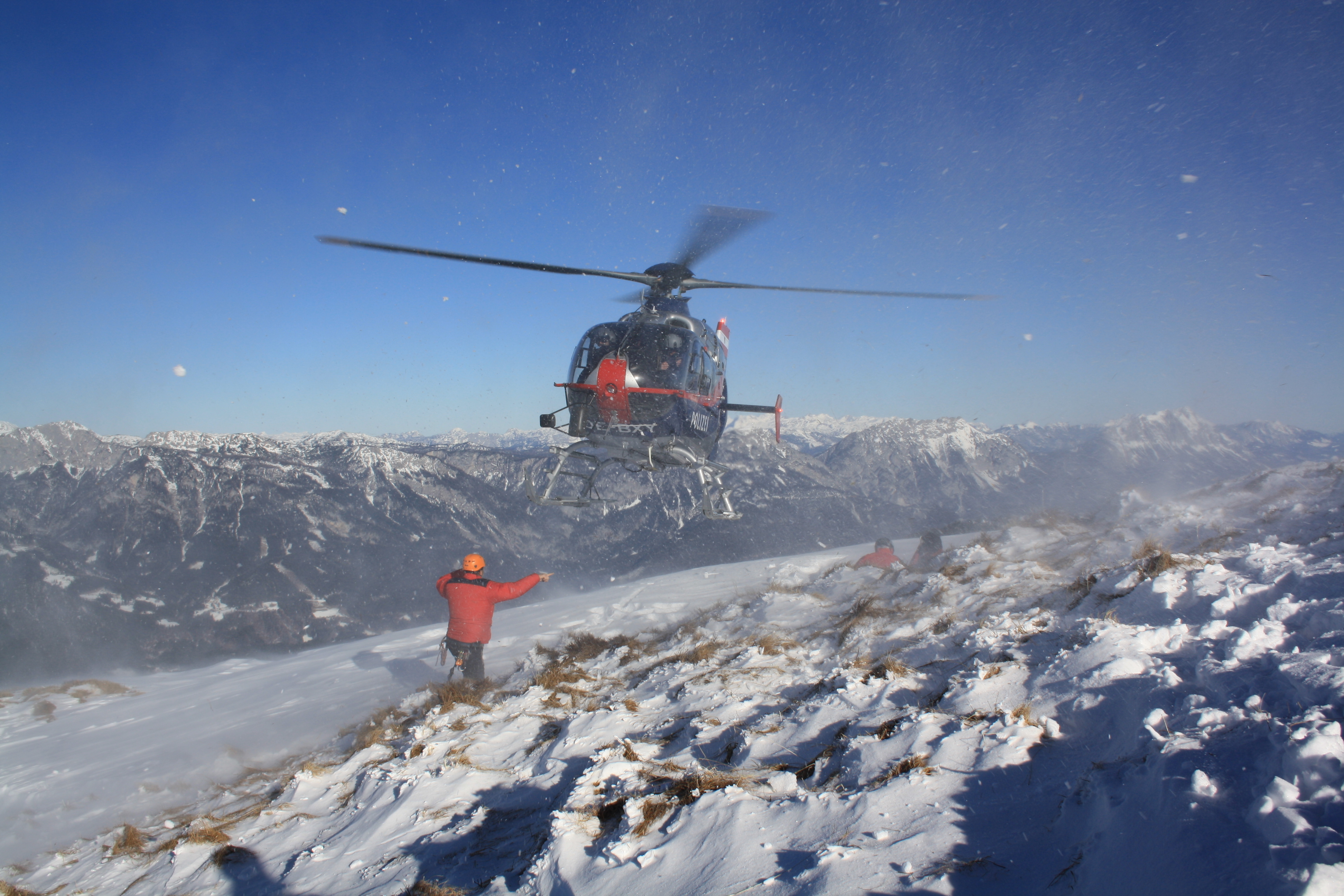 Helicopter in flight over snow covered mountain region.